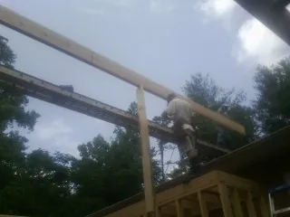 Carpenter setting a ridge beam over a new addition frame — Ice Dam Removal by Roofing Brothers in Lostant