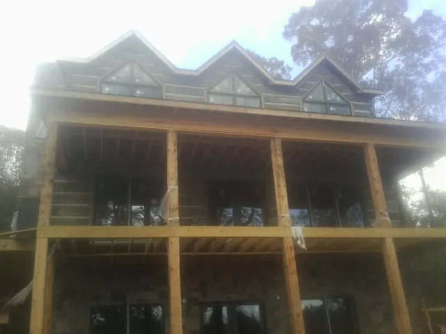 Dormers and porch framing on a large log home under construction — Roof Coating work by our crew in Lostant