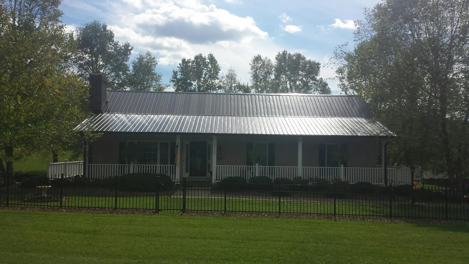 Gray metal roof on a brick ranch with a full width front porch — Gutter Guard Installation work by our crew in Lostant