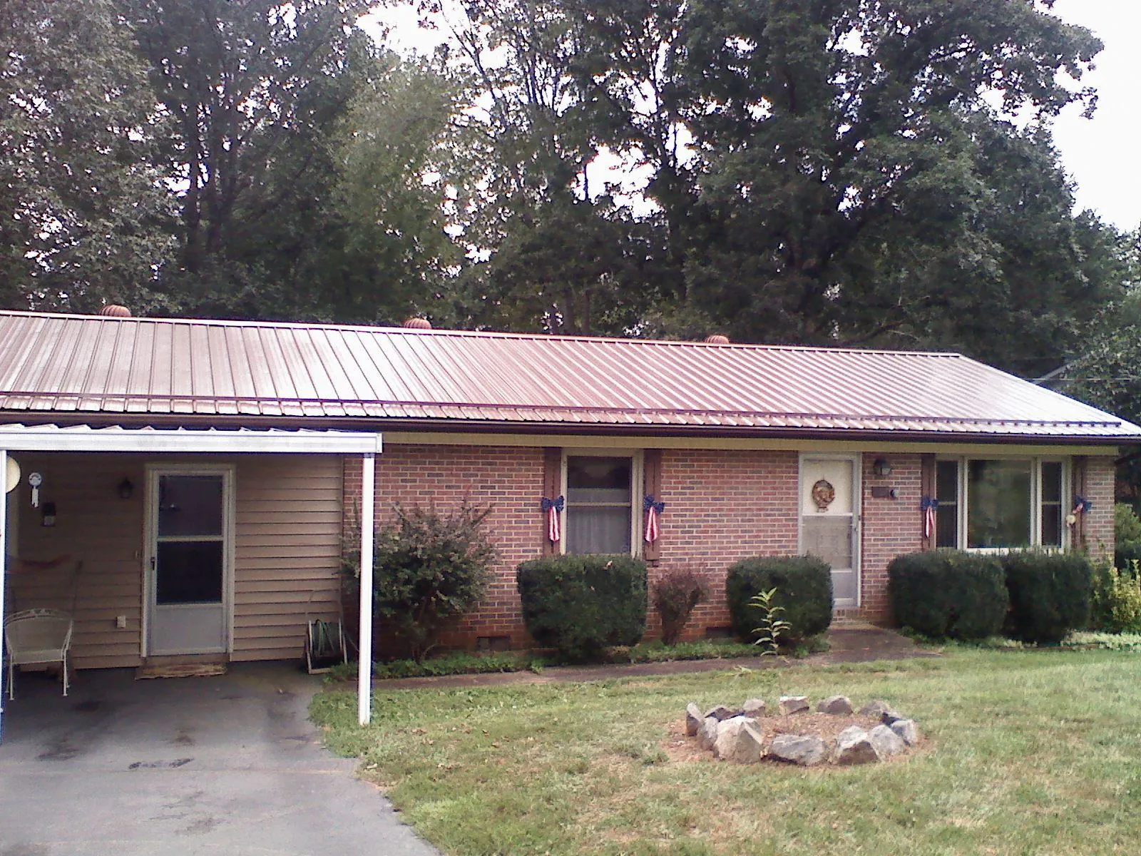 Bronze metal roof and carport on a brick ranch home — Roof Repair work by our crew in Lostant